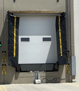 Worn dock shelter in need of replacement components like verticals and horizontals. Truck shelter impact damage showing replacement dock shelter components and fiberglass side panel